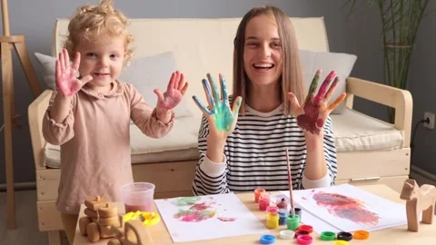 Extremely happy charming mommy with her small daughter painting together in Vídeo Stock 252800251