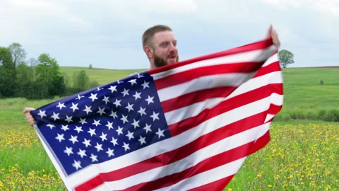 Extremely happy satisfied bearded man holding in hands big American flag Stock Footage 154582857