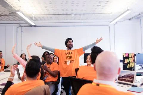 Exuberant hackers cheering, coding for charity at hackathon Stock Photos