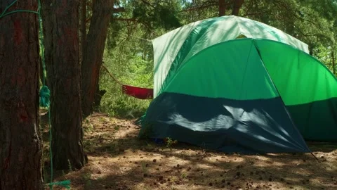 Eye angle view of touristic tent and swinning hammock behind with a person in it Stock Footage 144000092