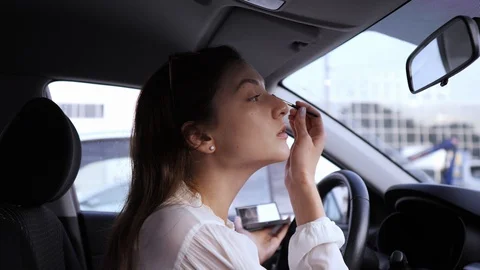 Eye brush, shadows, make-up in the car. A young woman looks in the mirror inside Stock Footage 120948708