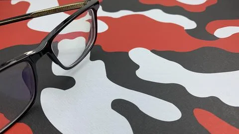 Eye catching eyeglasses with black frames laying on a red, white and black Stock Photos