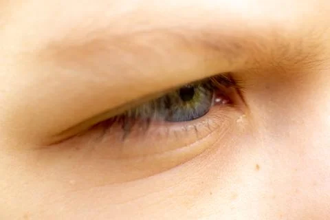 The eye of a child squints in the sun close-up shot. Stock Photos