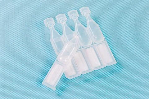 Eye drops in small disposable plastic ampoules, one open ampoule Foto stock