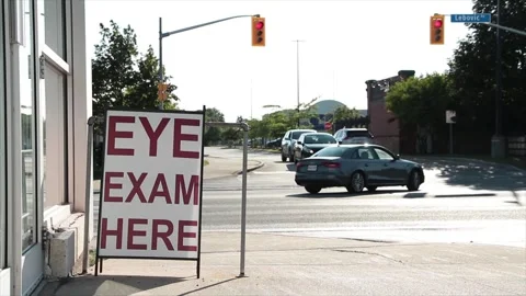 Eye exam here writing text caption sandwich board sign in front of store Video stock 249100034