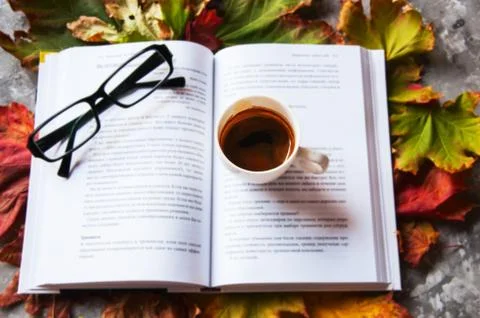 Eye glasses, book and cup of espresso on a maple leaves Stock Photos