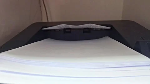 This eye-level close-up shows a printer's output tray with newly printed 스톡 동영상 313752315