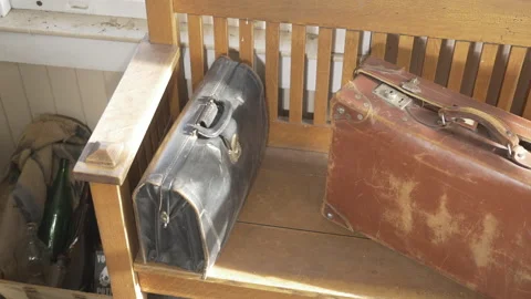 Eye level slider shot of old vintage travelling suitcases sitting  old stool Stock Footage 146013366