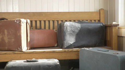 Eye level slider shot of old vintage travelling suitcases sitting on a old wo Stock Footage 146015108