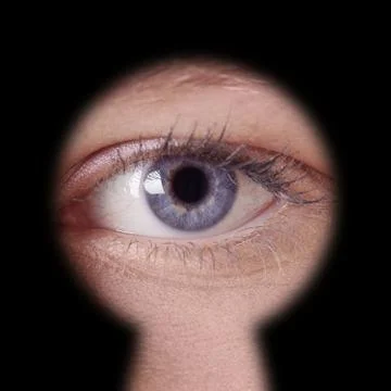 Eye looking through keyhole Stock Photos