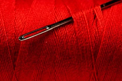 Eye of the needle with red polyester thread. Spool of red polyester sewing .. 写真素材