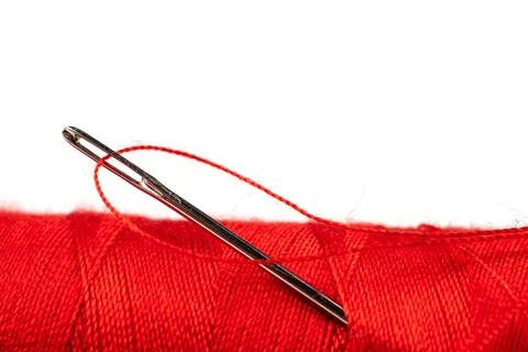 Eye of the needle with red polyester thread. Spool of red polyester sewing .. 写真素材