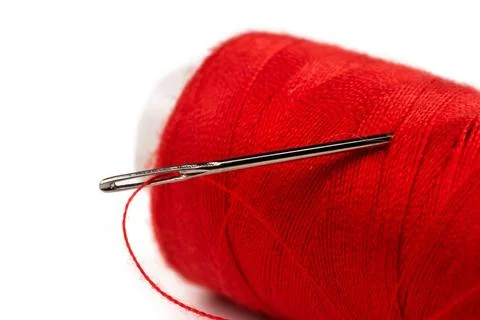 Eye of the needle with red polyester thread. Spool of red polyester sewing .. 写真素材