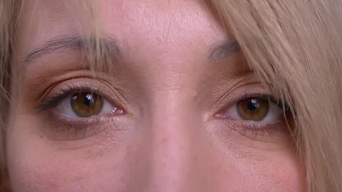 Eye portrait of middle-aged blonde short-haired model watches calmly into camera Stock Footage 108681342