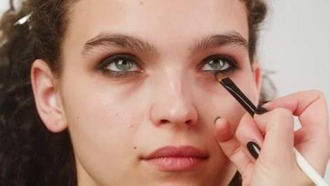 Eye shadow makeup to the upper eyelid, close-up. Makeup artist applies a bright Stock Footage 274146381