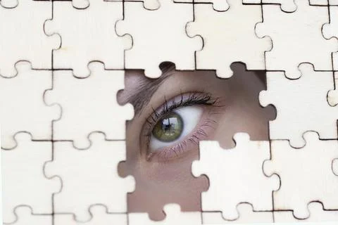 Eye watching through puzzles. Close-up of the girl's eye looking through the Stock Photos