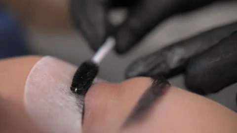 Eyebrow and eyelash master combing eyelashes before an eyelash extension pro Stock Footage 198881210