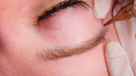 Eyebrow artist performs microblading procedure on client brow Stock Footage 278317596