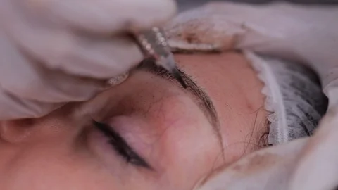 Eyebrow dusting pigment. Special machine with a needle puts paint. Close-up. 4K Stock Footage 106896616