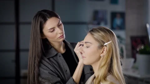 Eyebrow master makes eyebrow correction for a young blonde woman in a beauty Stock Footage 236471267