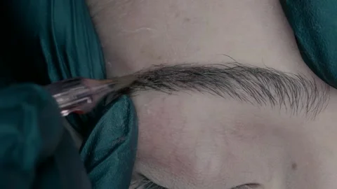 An eyebrow master in microblading makes a pigment at the edge of the eyebrow Stock Footage 223154890