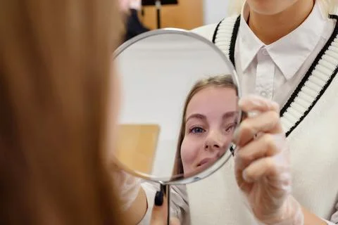 The eyebrow master shows the client the result of work in the mirror Stock-Fotos