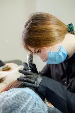 Eyebrow microblading. A master in black gloves holds a blending needle over t Stock Photos