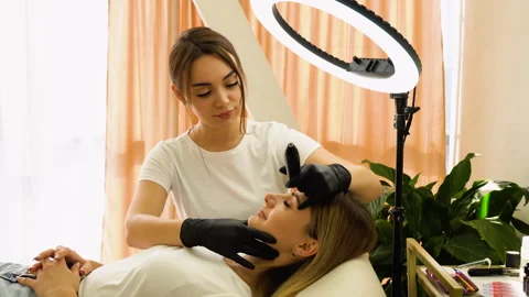 Eyebrows tattoo or Permanent Makeup. Young woman during procedure of permanent Stock Footage 255284881