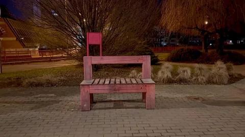 An eyecatching unique pink bench is beautifully illuminated at night within.. Stock Photos