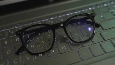 Eyeglass rotating view on laptop keyboard footage Stockbeeldmateriaal 290950179