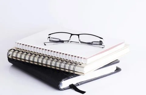 Eyeglass on top books stack Isolated on white background Stock Photos