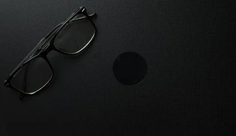 Eyeglasses And Dark Circular Shape On Black Textured Background 库存照片