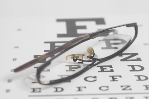 Eyeglasses on eyesight test chart background. Stock-Fotos
