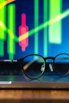 Eyeglasses in front of candlestick chart. Vertical finance and trading comp.. Stock Photos