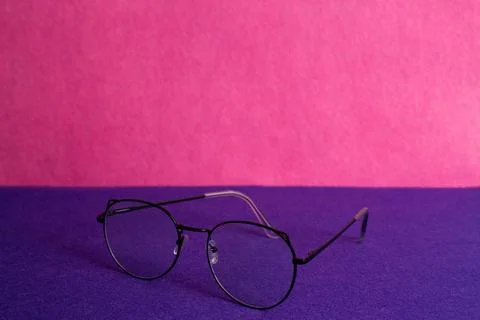 Eyeglasses, glasses in thin, black frames on a purple and pink background Stock Photos