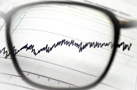 Eyeglasses highlighting a fluctuating line graph, symbolizing market analys.. Fotos de archivo