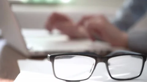 The eyeglasses lie on the table in front of the laptop. Stock Footage 173418495