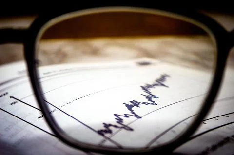 Eyeglasses magnifying a financial graph with sharp focus, symbolizing data .. 스톡 사진