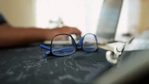 Eyeglasses on Map with Laptop in Background Stock Footage 320725171