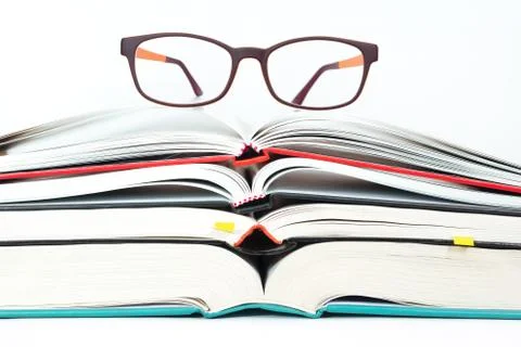 Eyeglasses on stack of open books Stock Photos