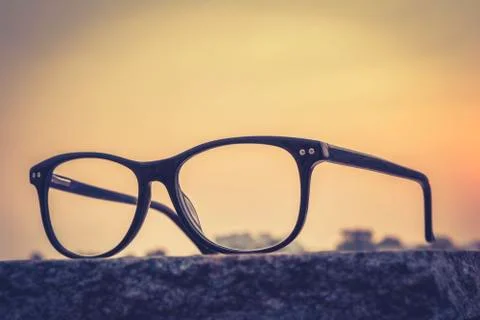 Eyeglasses on table with sunset background Stock Photos