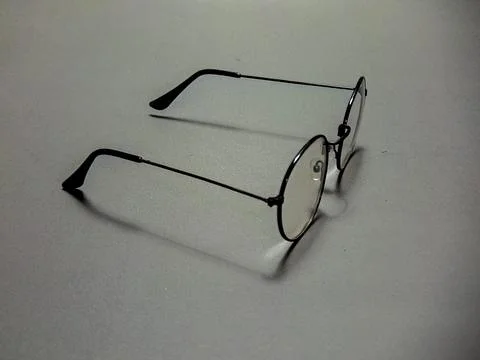 Eyeglasses with a thin black metal frame and round lenses rest on a gray su.. Stock Photos