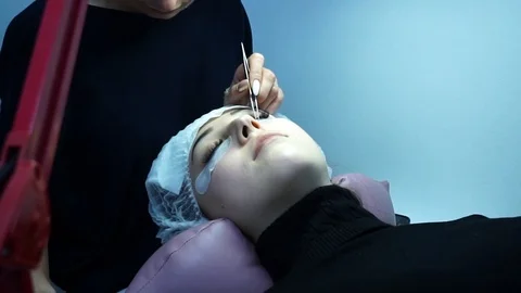 Eyelash extension. Master make-up artist extends eyelashes to a young girl. The Stock Footage 87434823