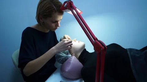 Eyelash extension. Master make-up artist extends eyelashes to a young girl. The Stock Footage 87452042