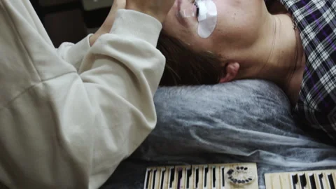 An eyelash extension master serves a client lying on a cosmetic table. Stock Footage 171853076