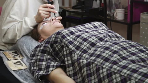 An eyelash extension master serves a client lying on a cosmetic table. Stock Footage 171853386