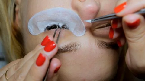 Eyelash extension procedure. The master grows long eyelashes. Female with ext Stock Photos