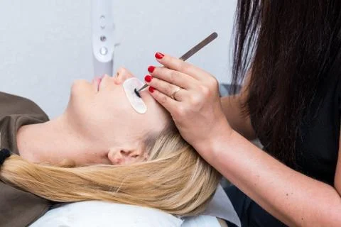Eyelash extension procedure. The master grows long eyelashes. Female with Stock Photos