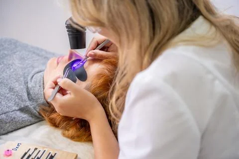 Eyelash extension procedure using ultraviolet lamp in modern beauty salon Stock Photos