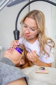 Eyelash extension procedure using ultraviolet lamp in modern beauty salon Stock Photos